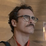 Joaquin Phoenix gazes off into the middle distance as Scarlett Johansson whispers dialogue in a recording booth